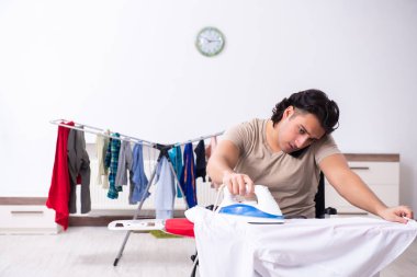 Tekerlekli sandalyedeki genç adam evde ütü yapıyor.