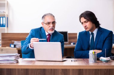 Genç ve yaşlı çalışanlar ofiste birlikte çalışıyorlar.
