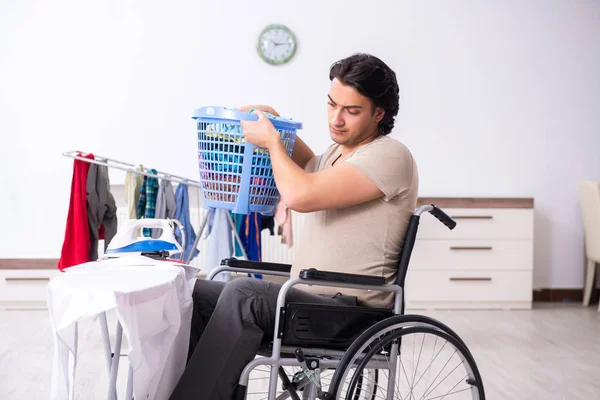 Молодой человек в инвалидной коляске гладит дома — стоковое фото