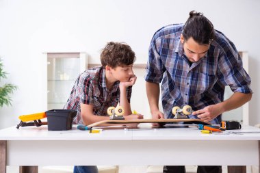 Genç baba oğluyla kaykay tamir ediyor.