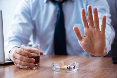 İş yerinde alkol ve sigara içen bir erkek işçi.