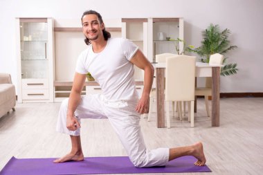 Genç adam evde fiziksel egzersiz yapıyor.