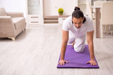 Genç adam evde fiziksel egzersiz yapıyor.