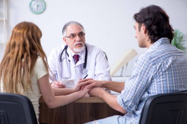 Genç çift yaşlı erkek doktoru ziyaret ediyor.