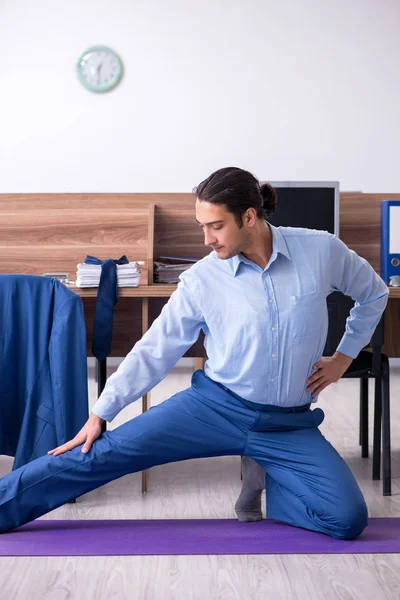 Junger gutaussehender Geschäftsmann macht Übungen am Arbeitsplatz — Stockfoto