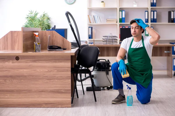 Jovem empreiteiro bonito limpando o escritório — Fotografia de Stock