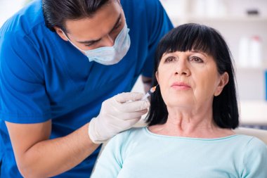 Yaşlı kadın estetik ameliyat için erkek doktoru ziyaret ediyor.