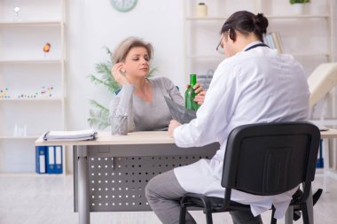 Alkolik kadın, genç erkek doktoru ziyaret ediyor.