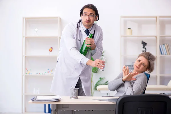 Kvinnlig alkoholist besöker ung manlig läkare — Stockfoto