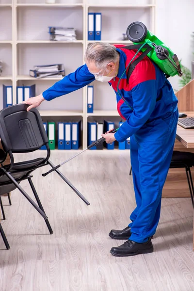 Velho empreiteiro profissional fazendo controle de pragas no escritório — Fotografia de Stock