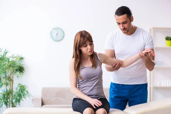 Mujer joven que visita al médico fisioterapeuta masculino — Foto de Stock