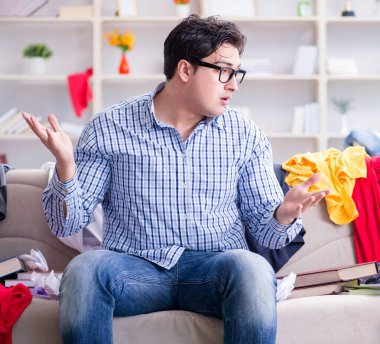 Genç adam dağınık bir odada çalışıyor.