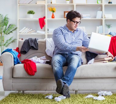 Genç adam dağınık bir odada çalışıyor.