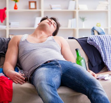 Dağınık bir odada alkol alan genç bir öğrenci.