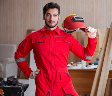 Kaynak tabancası elektrot ve kask takan genç bir tamirci.