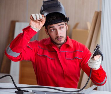 Kaynak tabancası elektrot ve kask takan genç bir tamirci.