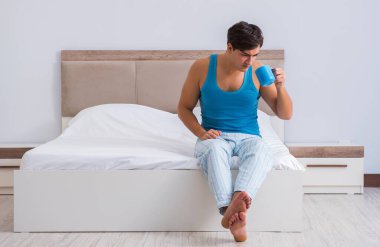 Genç adam yatakta uyanıyor.