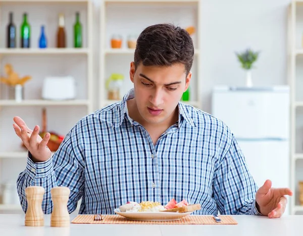 Jovem marido comendo comida insípida em casa para o almoço — Fotografia de Stock