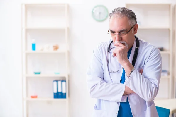 Old male doctor working in the clinic