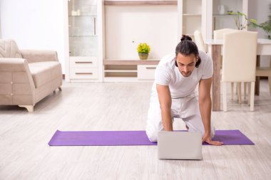 Genç adam evde fiziksel egzersiz yapıyor.