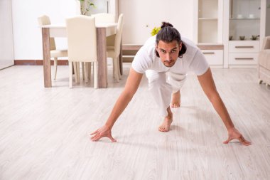 Genç adam evde fiziksel egzersiz yapıyor.