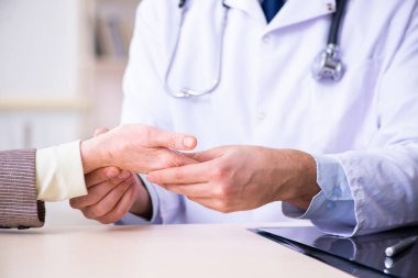 Genç doktor yaşlı yaşlı kadını muayene ediyor.