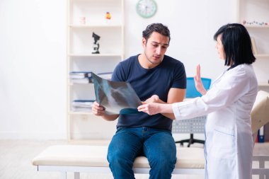 Genç erkek hasta yaşlı kadın doktoru ziyaret ediyor.