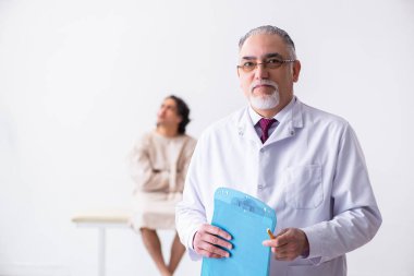 Genç hastayı muayene eden yaşlı erkek doktor psikiyatristi