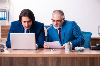 Genç ve yaşlı çalışanlar ofiste birlikte çalışıyorlar.