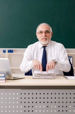 Tahtanın önünde yaşlı bir erkek öğretmen.