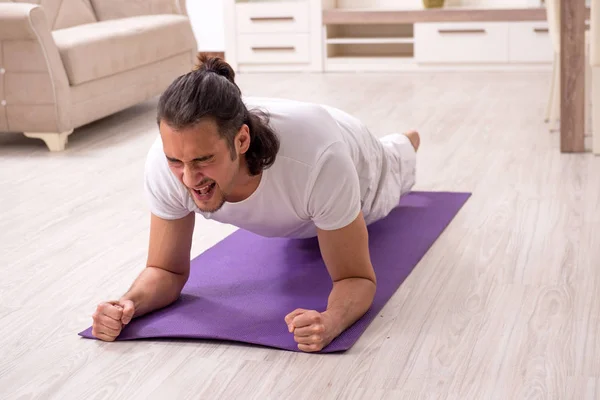 Jovem fazendo exercícios físicos em casa — Fotografia de Stock