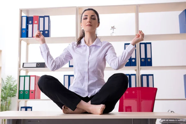 Jovem funcionária fazendo exercícios no escritório — Fotografia de Stock