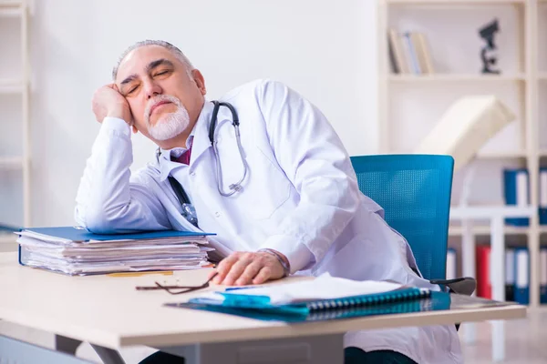 Old male doctor working in the clinic — Stock Photo, Image