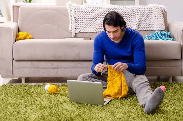 Young good looking man knitting at home