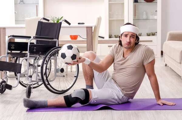 Injured young man doing exercises at home — Stock Photo, Image