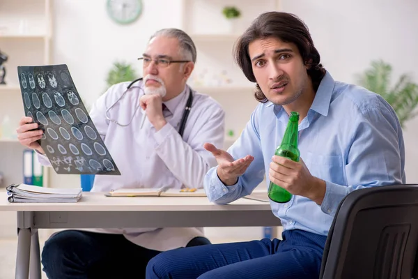 Young male alcoholic visiting old doctor — Stock Photo, Image