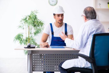 Genç erkek müteahhit yaşlı doktoru ziyaret ediyor.