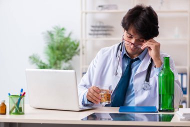 Genç erkek doktor ofiste içiyor.