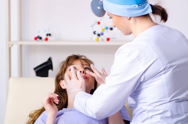 Kadın doktor otolaringolojisti ziyaret eden genç bir kadın.
