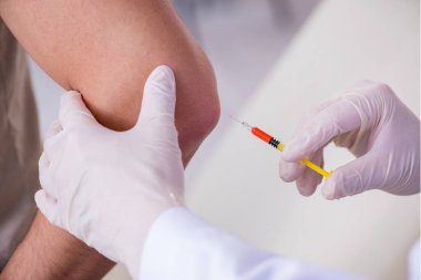 Erkek hasta aşı aşısı için doktoru ziyaret ediyor.