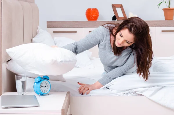 Jovem deitada na cama no conceito de gerenciamento de tempo — Fotografia de Stock