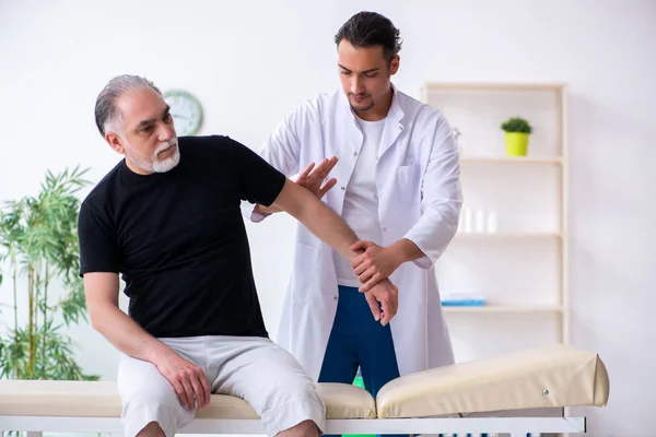 Oude gewonde man op bezoek bij jonge dokter — Stockfoto