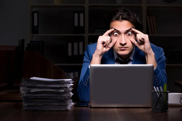 Young male employee working night in the office