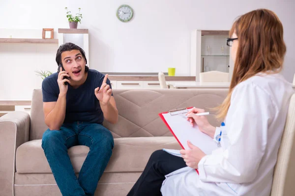 Jonge mannelijke patiënt in gesprek met vrouwelijke psycholoog persoonlijk — Stockfoto