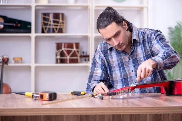 Junger gutaussehender Reparateur repariert Gitarre — Stockfoto