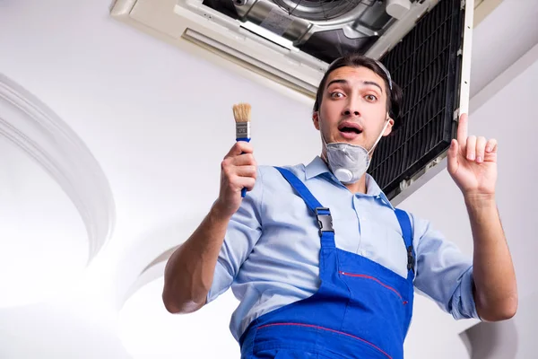 Ung reparatör reparera tak luftkonditionering enhet — Stockfoto