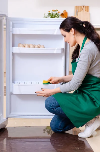 Fiatal nő takarítás hűtőszekrény higiéniai koncepció — Stock Fotó