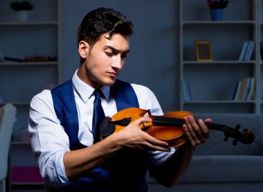 Genç müzisyen evde keman çalıyor.