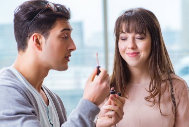 Güzellik salonunda güzel bir kadın için makyaj yapan adam.