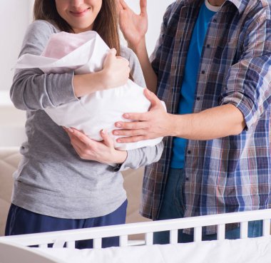 Yatağın yanında yeni doğmuş bebekleri olan genç ebeveynler.